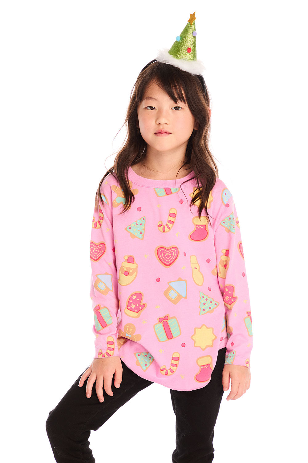 Girl wearing Chaser’s pink Tossed Candy Canes Long Sleeve with colorful candy cane designs and a Christmas tree hat on a white background