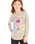 Girl wearing Chaser’s Heather Grey Colorful Smileys long sleeve pullover with colorful smiley face designs and black jeans on a white background