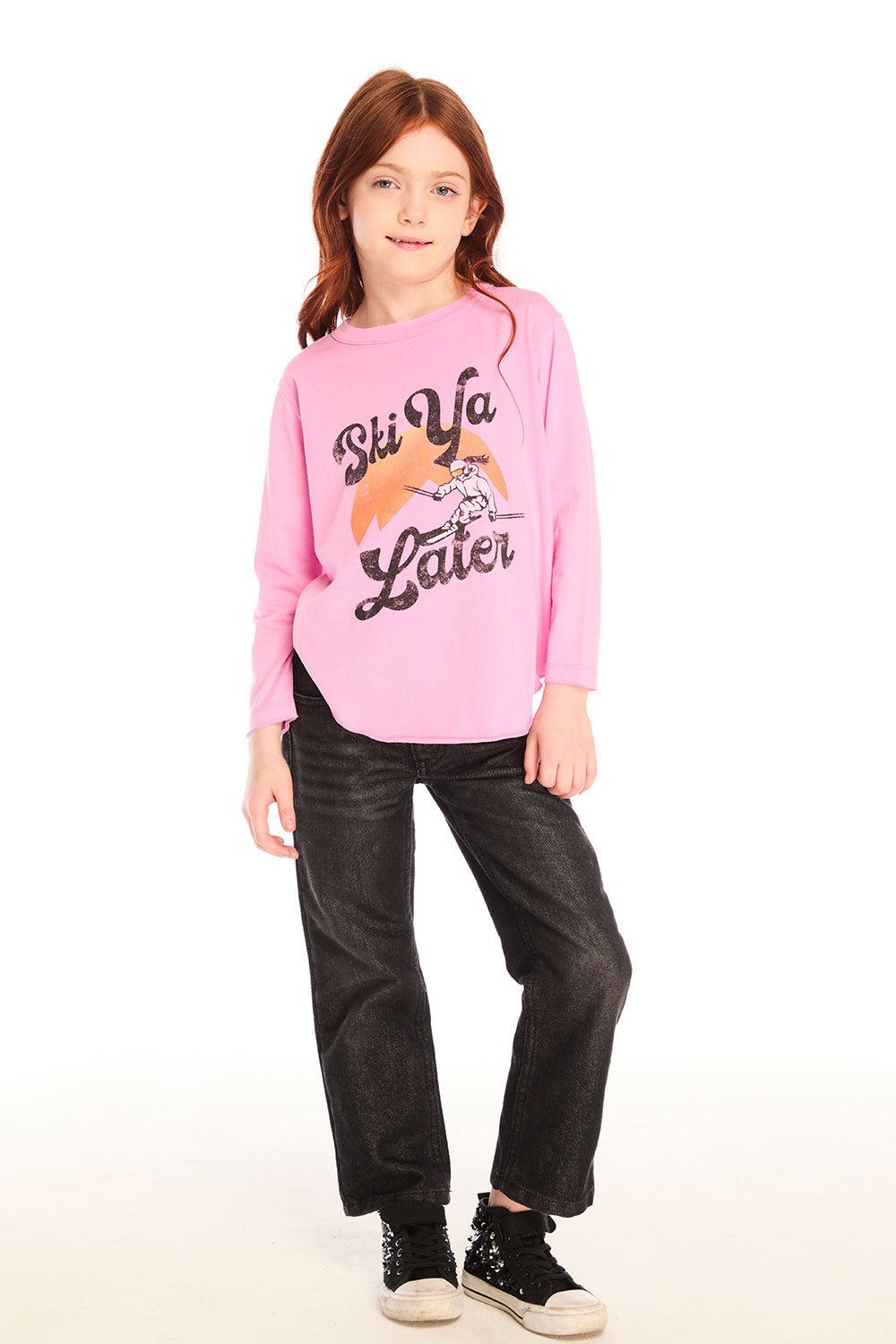 Full body view of girl wearing Chaser’s pink Ski Ya Later Long Sleeve with text and graphics and black jeans on a white background