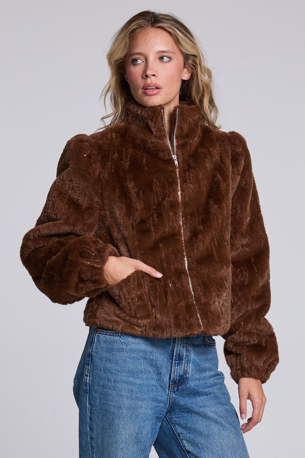 Model wearing Chaser's Dark Chocolate Puff Sleeve Jacket in deep brown plush faux-fur texture with oversized puff sleeves, angled view
