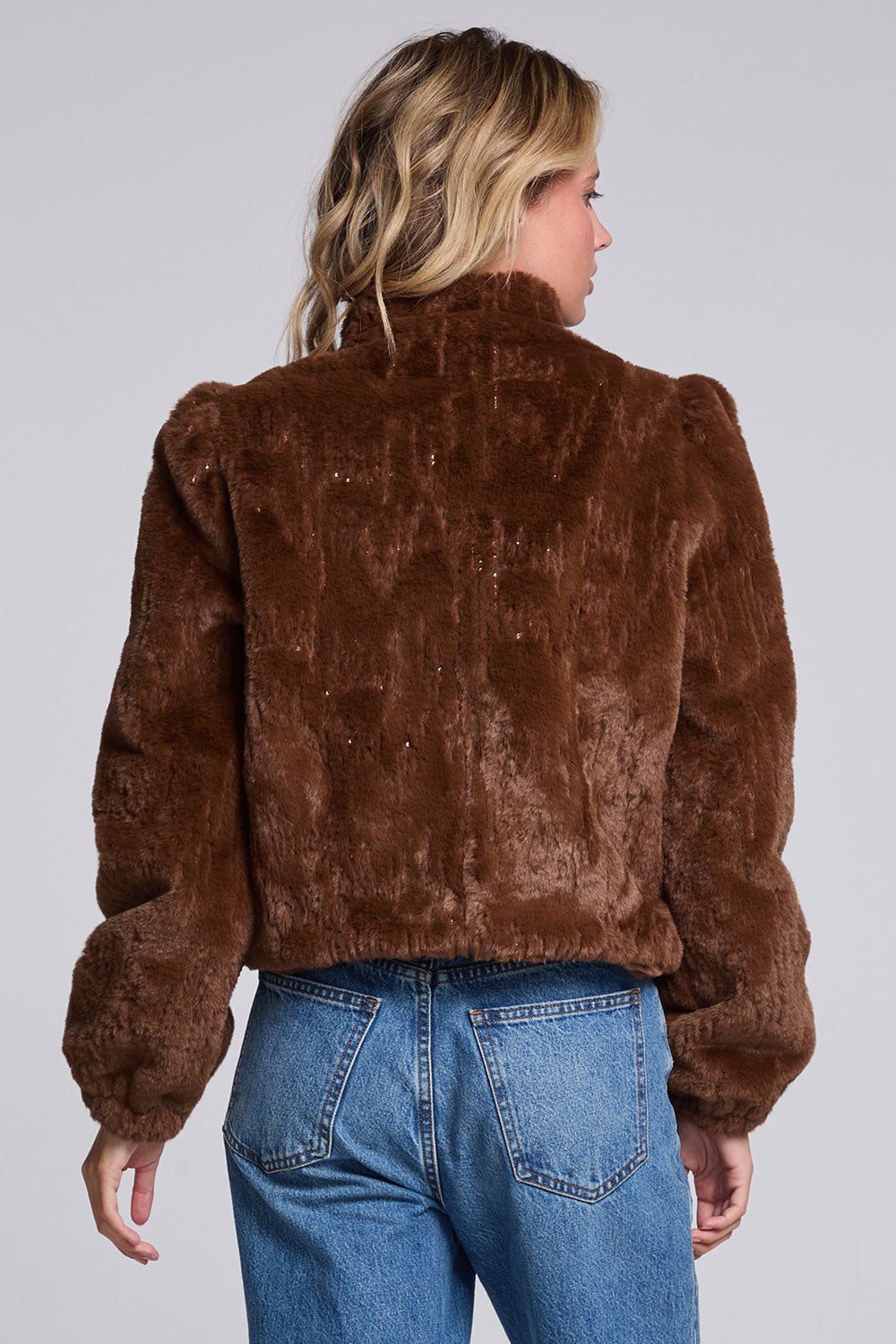 Model wearing Chaser's Dark Chocolate Puff Sleeve Jacket in deep brown plush faux-fur texture with oversized puff sleeves, back view
