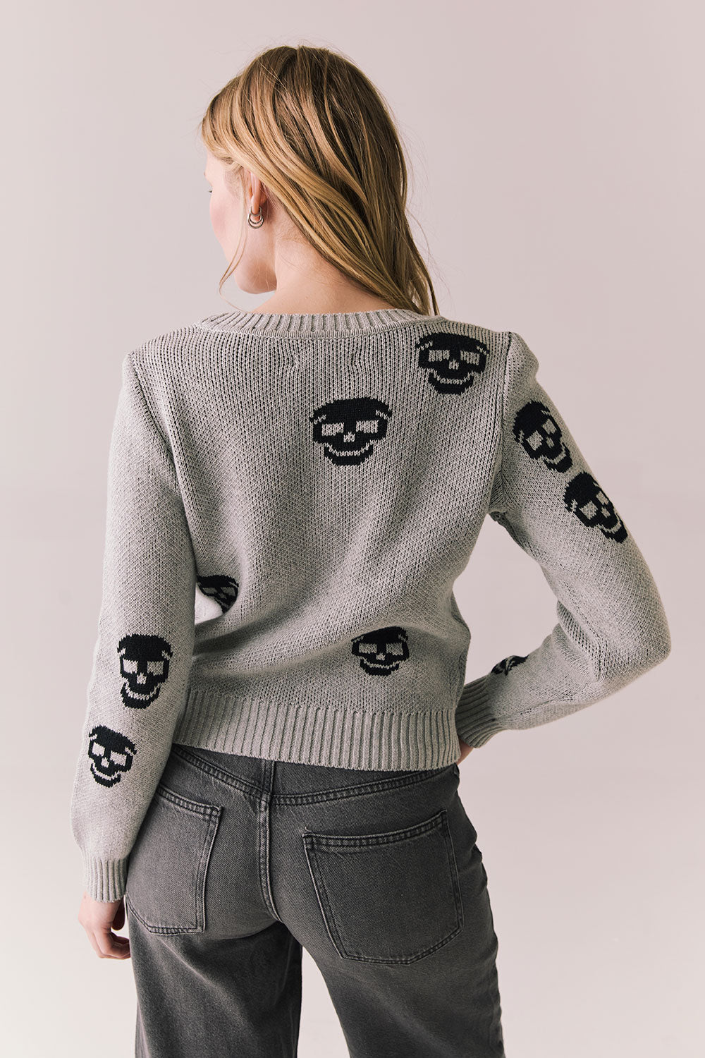 Back view of Tossed Skulls Long Sleeve sweater in Heather Grey with allover black skull motif and fitted silhouette against a plain background