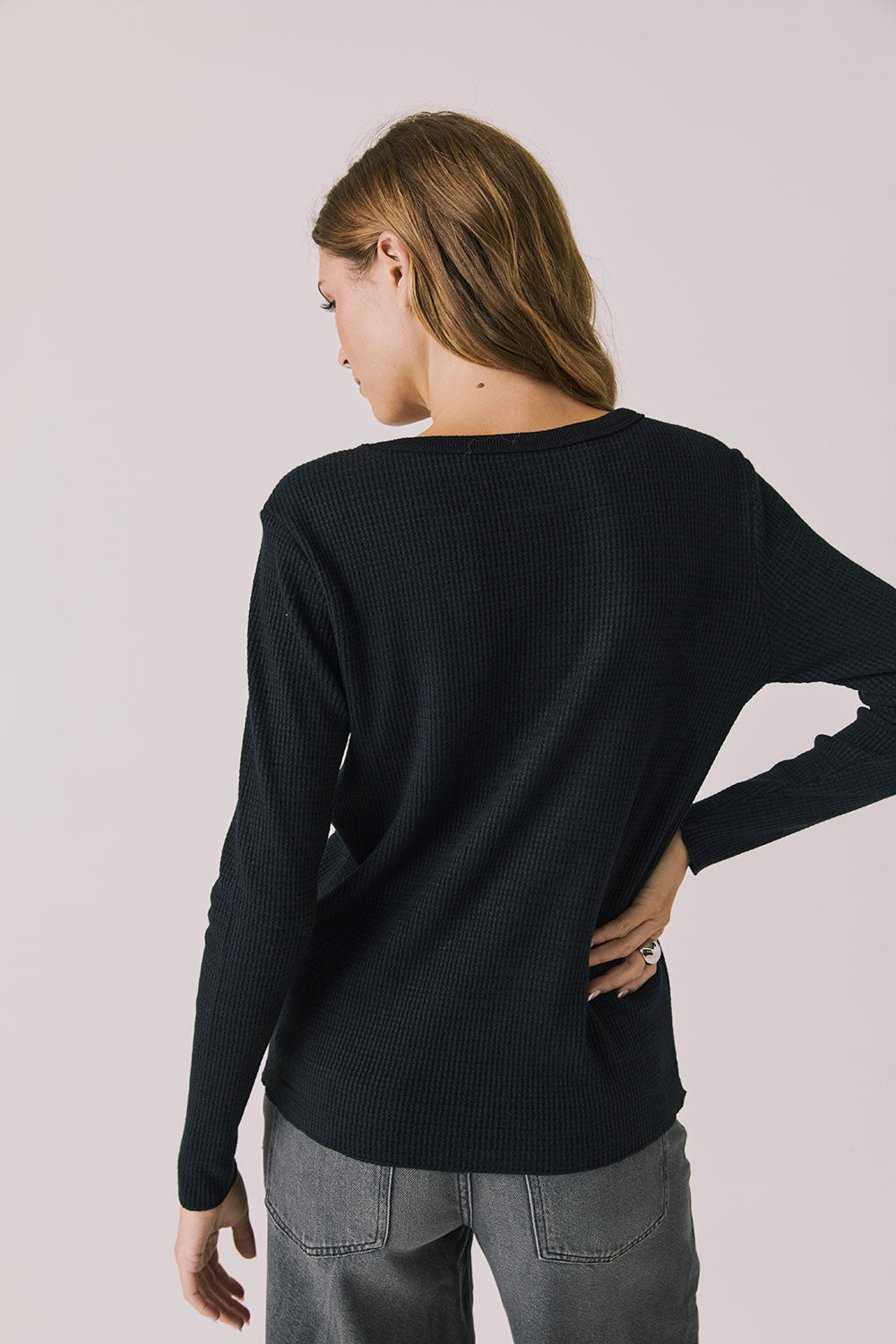 Back view of woman wearing Chaser's black Apres Ski Milano Military Thermal Long Sleeve Tee on a plain background