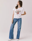 Woman wearing Chaser's white Blondie Live In Hollywood Tee and blue jeans on a plain background