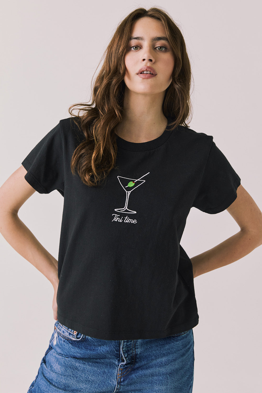 Front view of woman wearing Chaser’s black Tini Time Tee with martini glass graphic and “Tini Time” text on a plain background