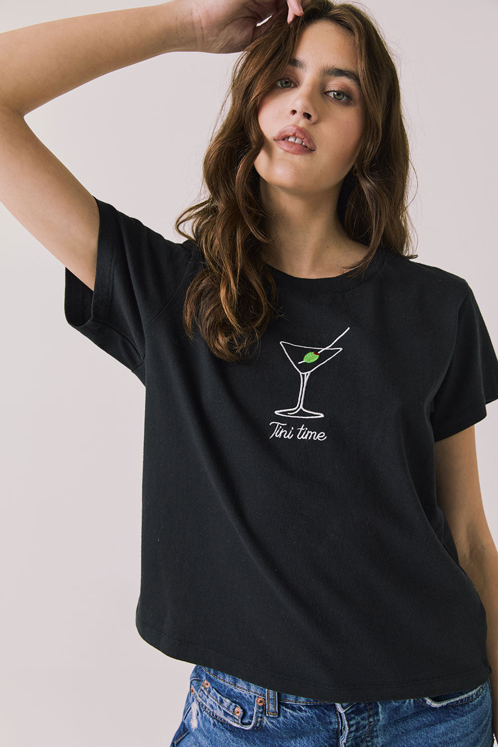 Front view of woman wearing Chaser’s black Tini Time Tee with martini glass graphic and “Tini Time” text on a plain background