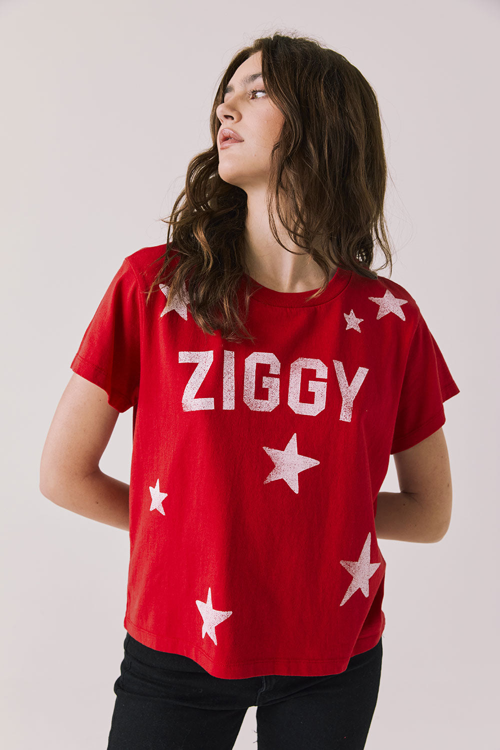 Front view of woman wearing Chaser’s Rouge Red David Bowie Ziggy Stardust Tee with white star designs on a light gray background (Licensed band collaboration — features official David Bowie branding for SEO relevance)