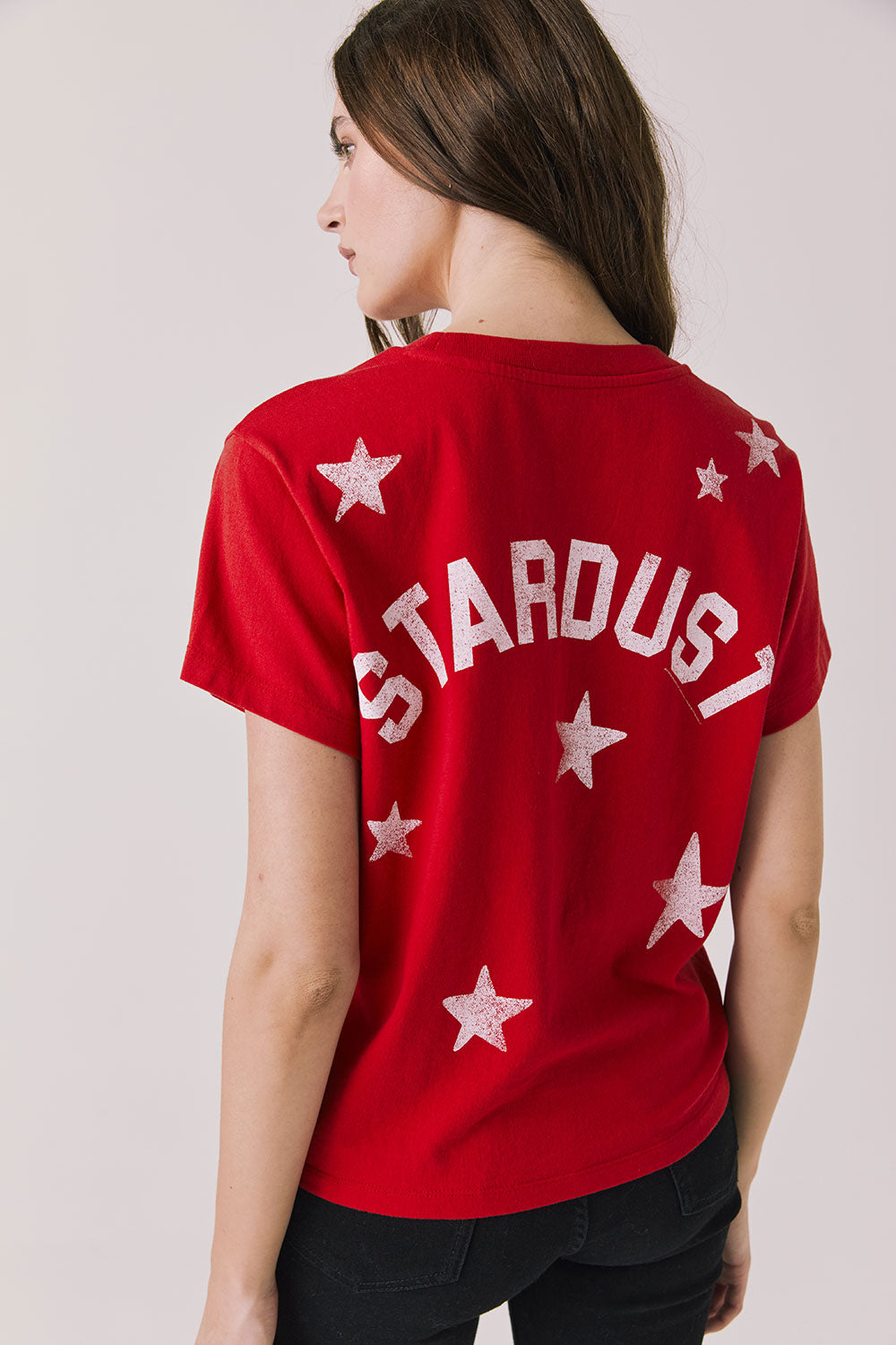 Back view of woman wearing Chaser’s Rouge Red David Bowie Ziggy Stardust Tee with 'STARDUST' printed on the back against a plain background (Licensed band collaboration — features official David Bowie branding for SEO relevance)