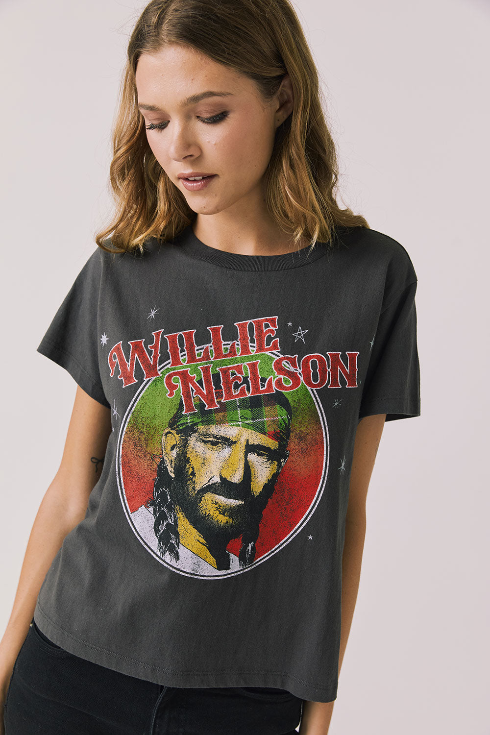 Front view of woman wearing Chaser’s Willie Nelson Willie Christmas Tee with colorful holiday graphic design on a plain background (licensed band collaboration)
