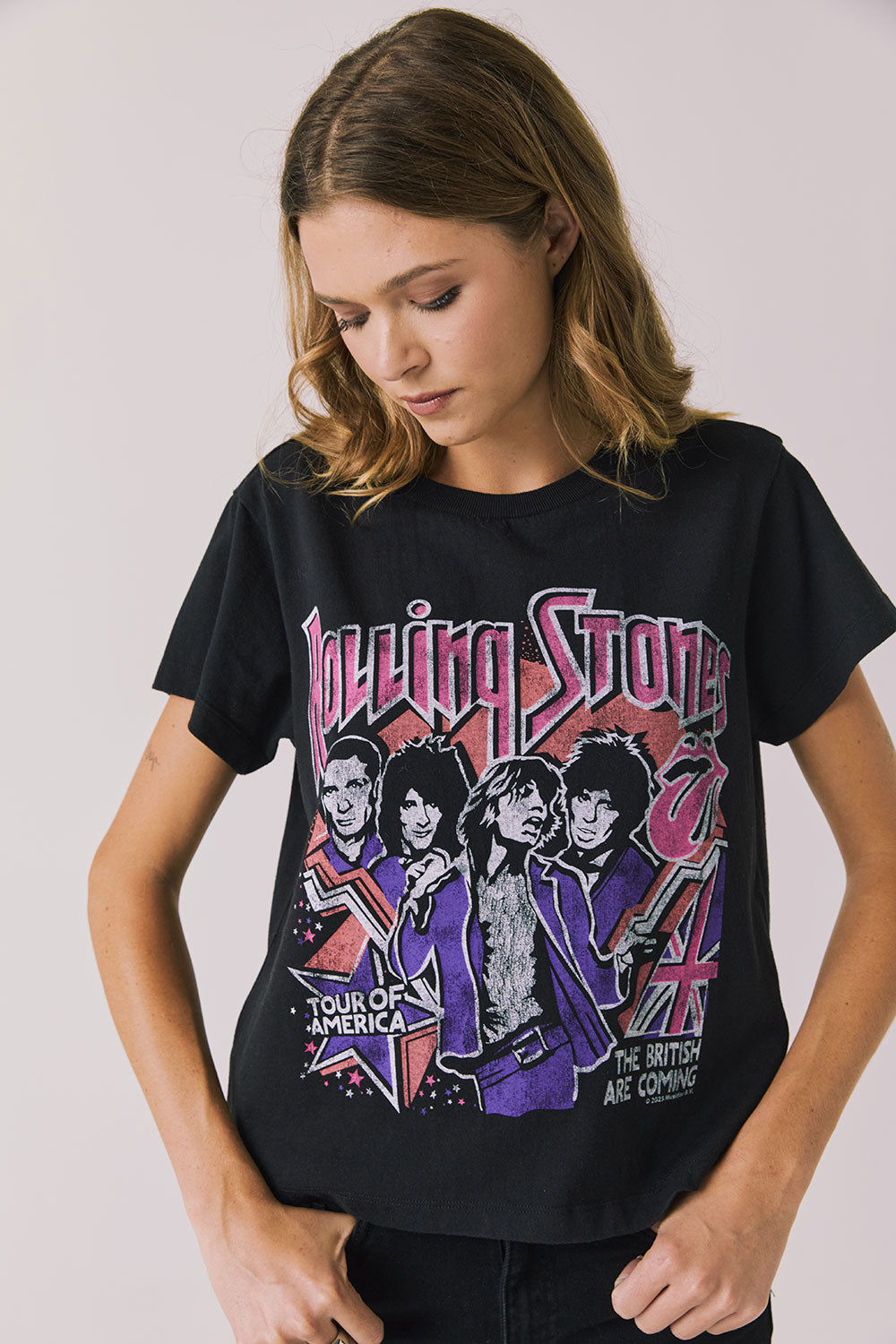 Front view of woman wearing Chaser’s The Rolling Stones The British Are Coming Tee in True Black with Union Jack, band logo, and band member graphics on a plain background