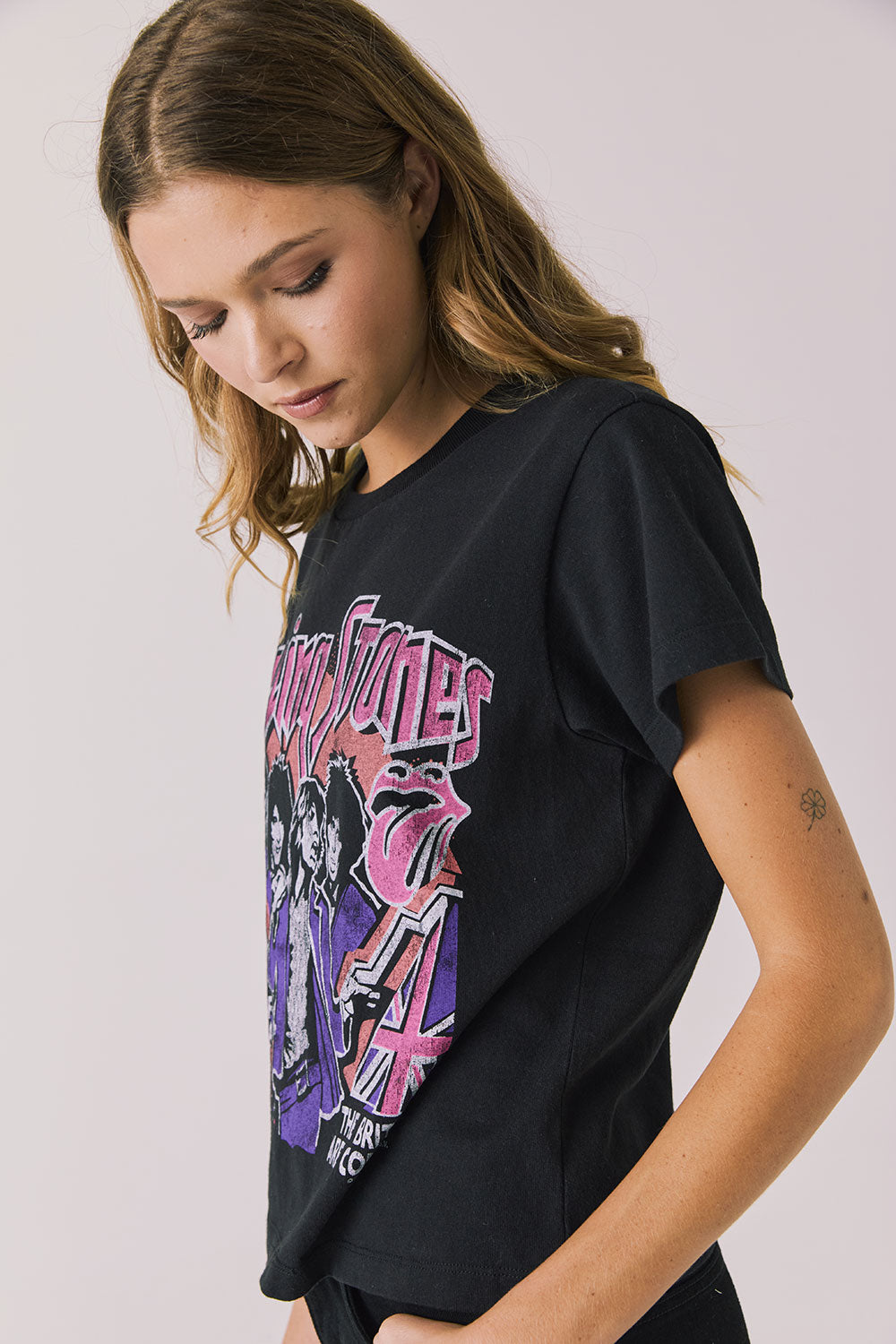 Side view of woman wearing Chaser’s The Rolling Stones The British Are Coming Tee in True Black on a plain background