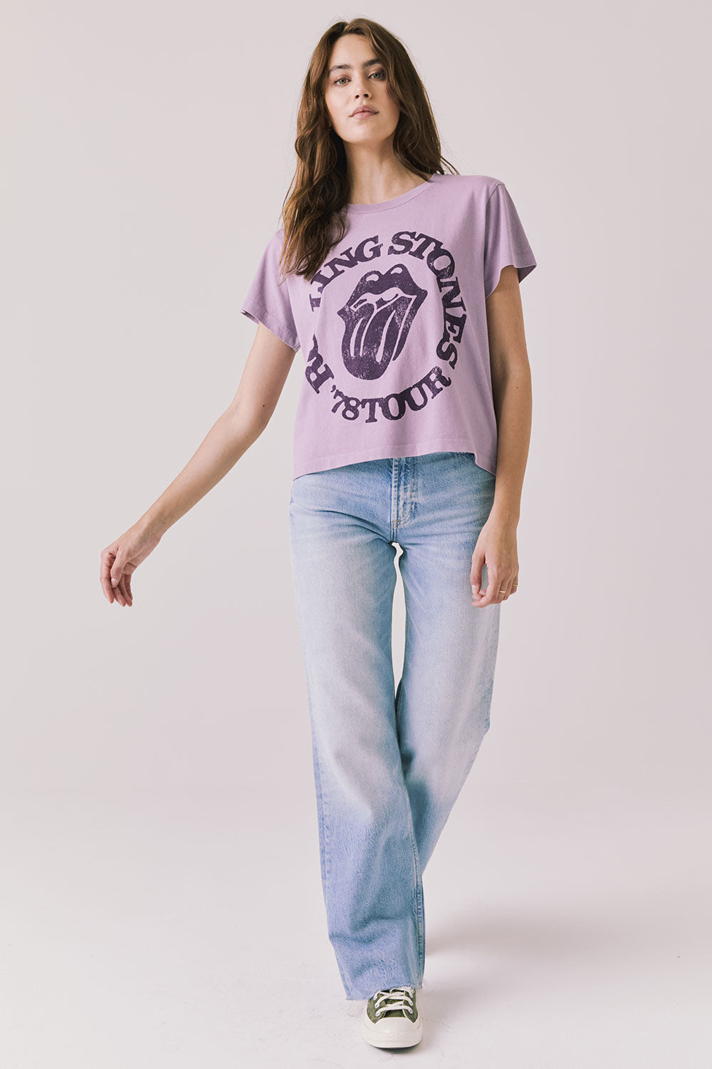 Full body view of woman wearing Chaser’s The Rolling Stones ’78 Tour Amethyst Purple Tee with jeans on a plain background