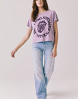 Full body view of woman wearing Chaser’s The Rolling Stones ’78 Tour Amethyst Purple Tee with jeans on a plain background
