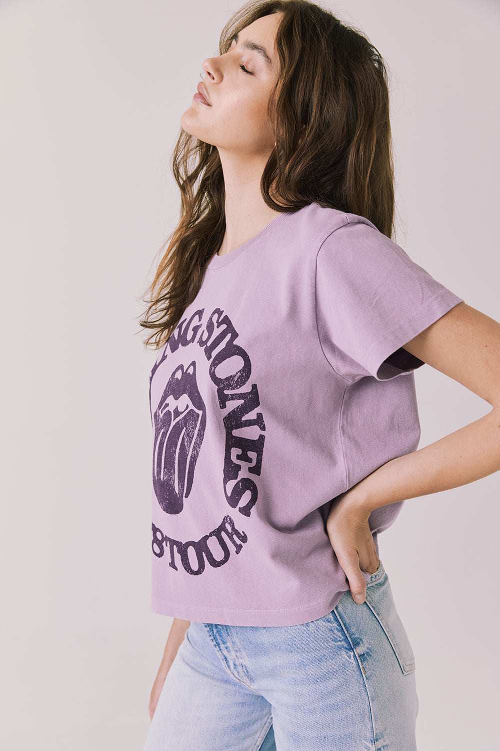 Side view of woman wearing Chaser’s The Rolling Stones ’78 Tour Amethyst Purple Tee on a plain background