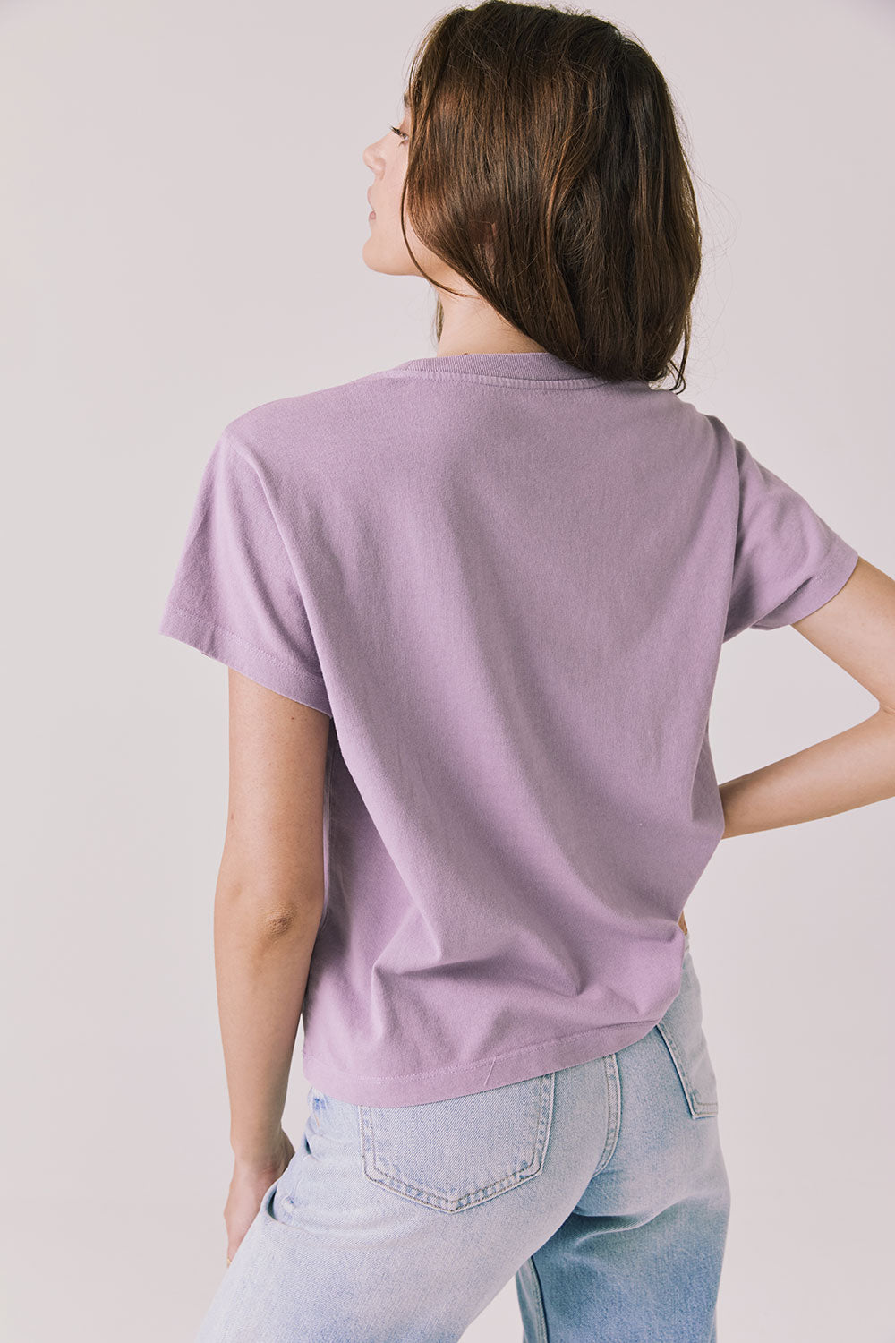 Back view of woman wearing Chaser’s The Rolling Stones ’78 Tour Amethyst Purple Tee on a plain background