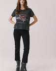 Full body view of woman wearing Chaser’s Tom Petty Live At The Fillmore Tee with black pants and boots on a plain background