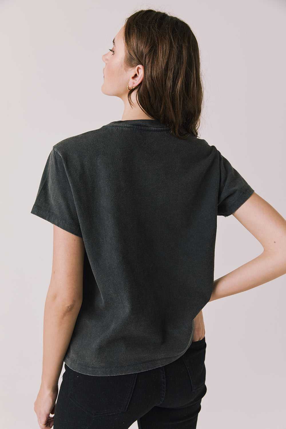 Back view of woman wearing Chaser’s Tom Petty Live At The Fillmore Tee on a plain background