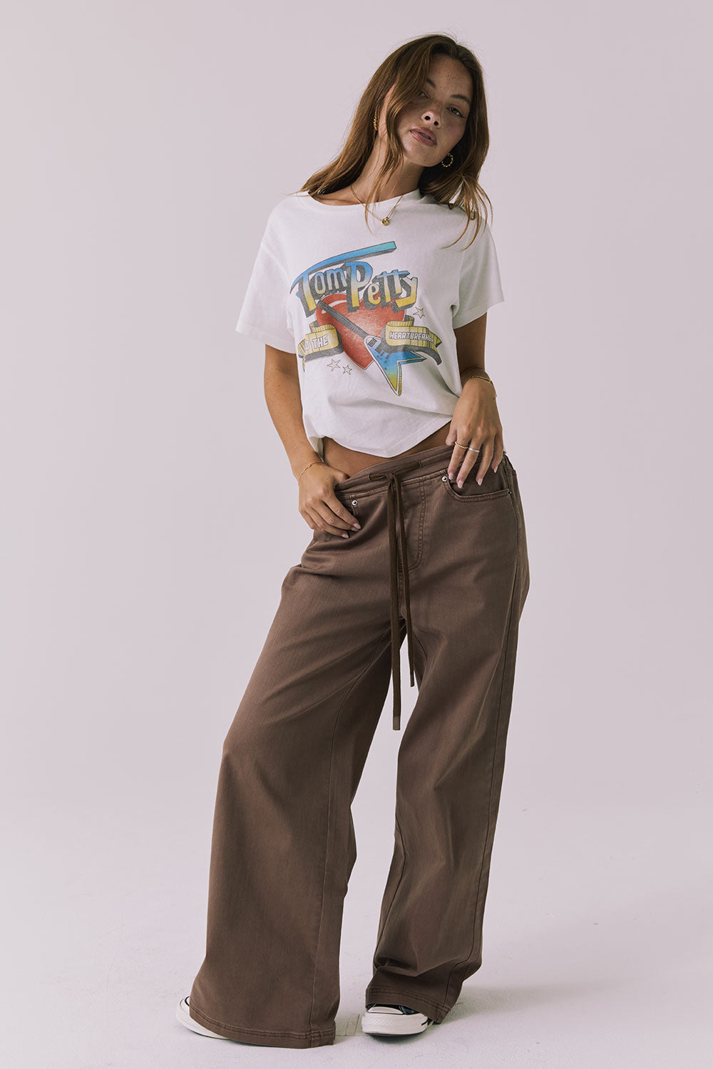 Full body view of the Chaser Layover Cognac Wash Jogger styled with Chaser's Tom Petty 1980 Tour white t-shirt and sneakers for an effortless laid-back look  on a plain background