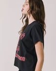 Side view of woman wearing Chaser’s Whiskey A Go Go Classic Neon Logo black Tee with red graphic text on a light background