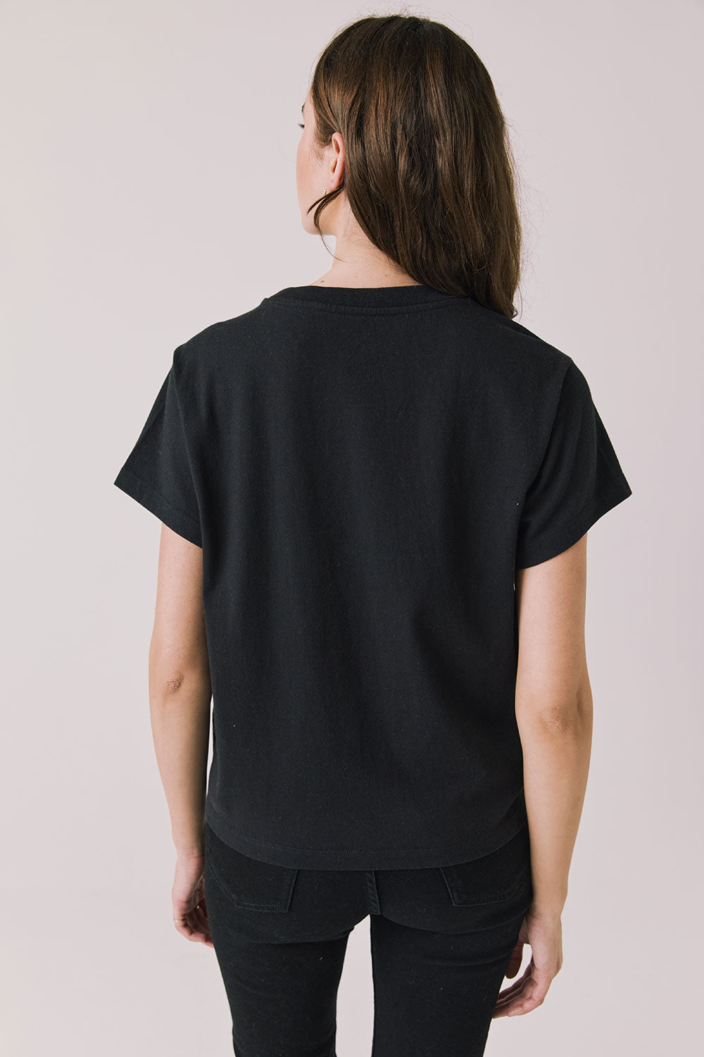 Back view of woman wearing Chaser’s Whiskey A Go Go Classic Neon Logo black Tee on a light background