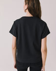 Back view of woman wearing Chaser’s Whiskey A Go Go Classic Neon Logo black Tee on a light background