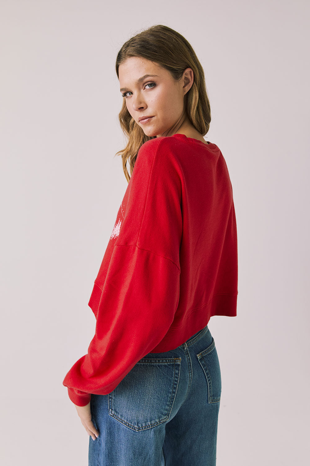 Back view of woman wearing Chaser's red Apres Ski Cheers with graphic design on a plain background