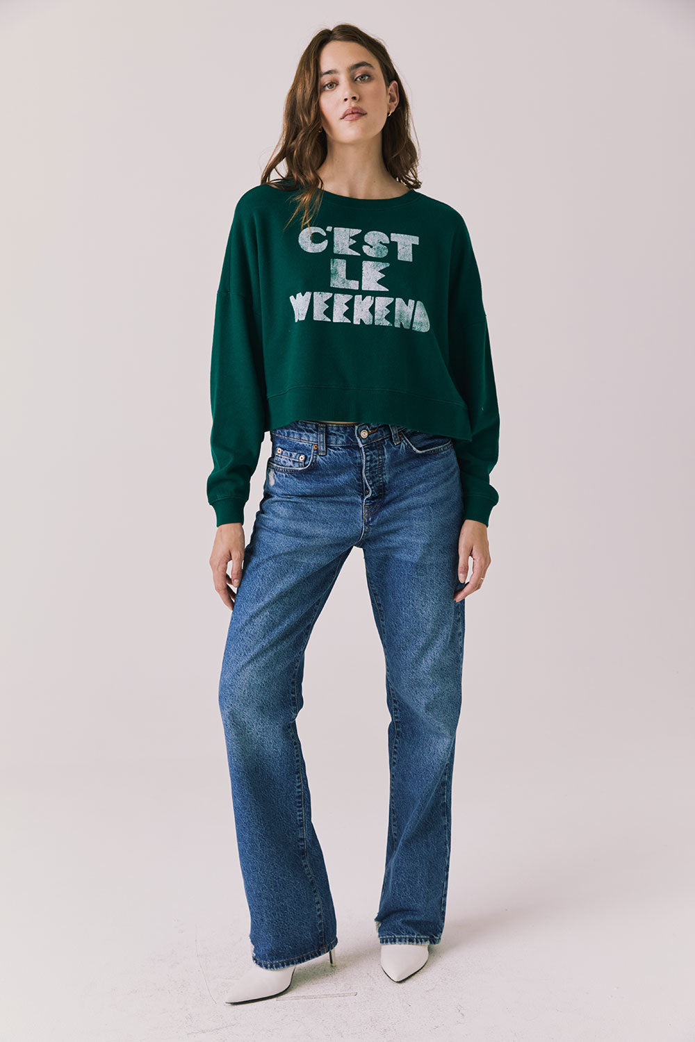 Full body view of woman wearing Chaser’s Blue Grass Green C’est Le Weekend Long Sleeve with blue jeans on a plain background