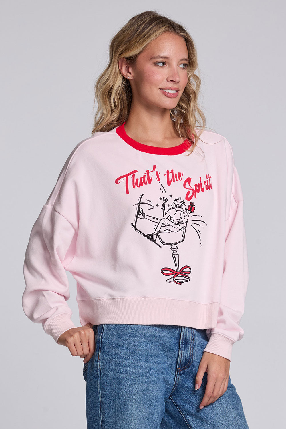Model wearing Chaser's Champagne Party Pullover in Pinky pink with festive champagne glass artwork, angled view