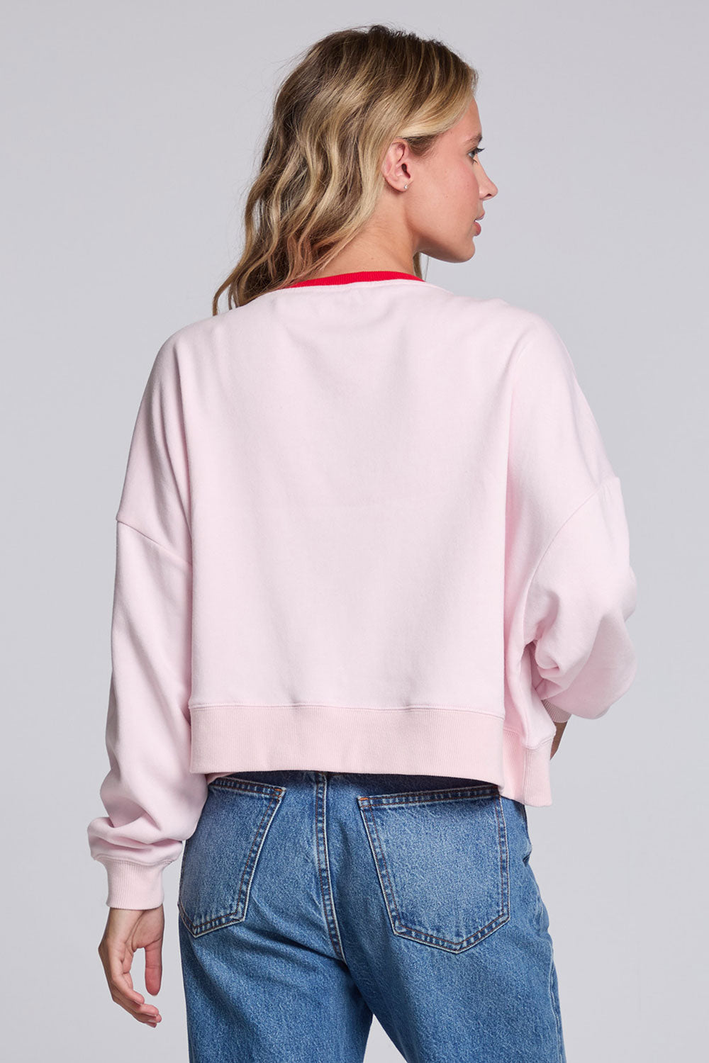 Model wearing Chaser's Champagne Party Pullover in Pinky pink with festive champagne glass artwork, back view