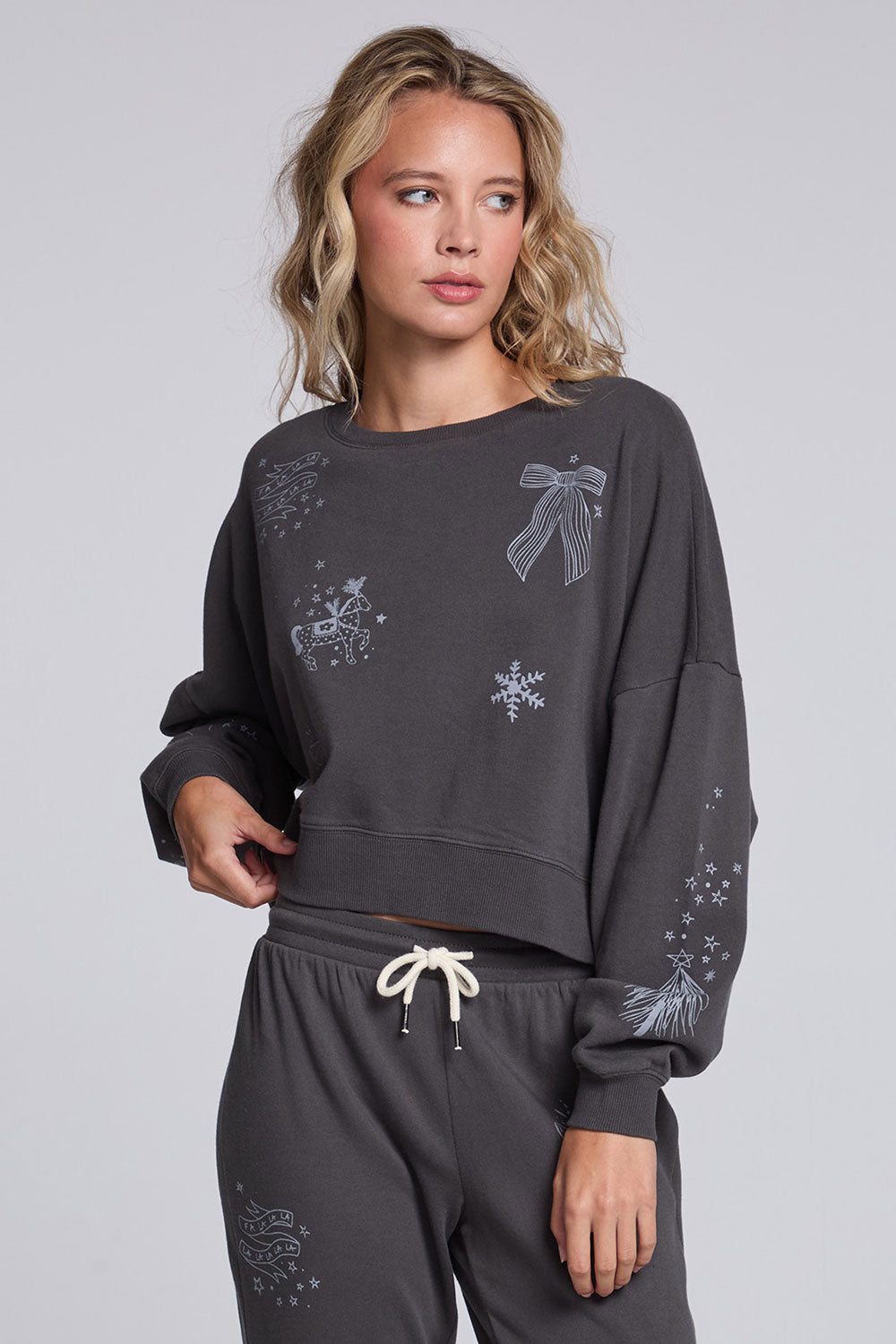 Model wearing Chaser's Holiday Cheer Pullover in Fresh Gravel with scattered holiday icons, front view
