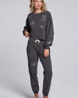 Model wearing Chaser's Holiday Cheer Pullover and matching Holiday Cheer Jogger in Fresh Gravel with scattered holiday icons, full-body view