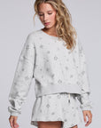 Model wearing Chaser's Twilight Pullover in Heather Grey with scattered black stars and spark details, angled view