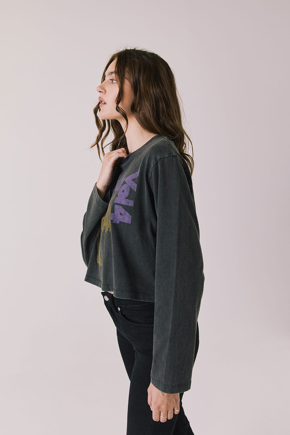 Side view of woman wearing Chaser's black oversized Black Sabbath Vol 4 Long Sleeve top with a graphic design, black pants on a white background