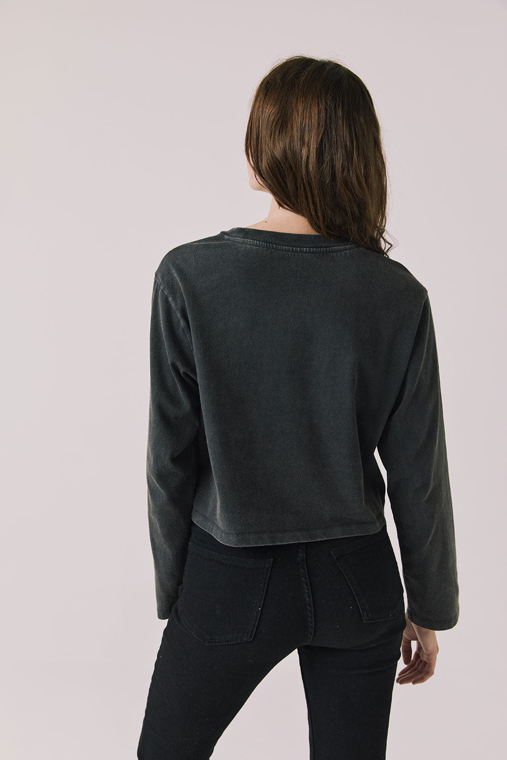 Back view of woman wearing Chaser's black oversized Black Sabbath Vol 4 Long Sleeve top with black pants on a white background