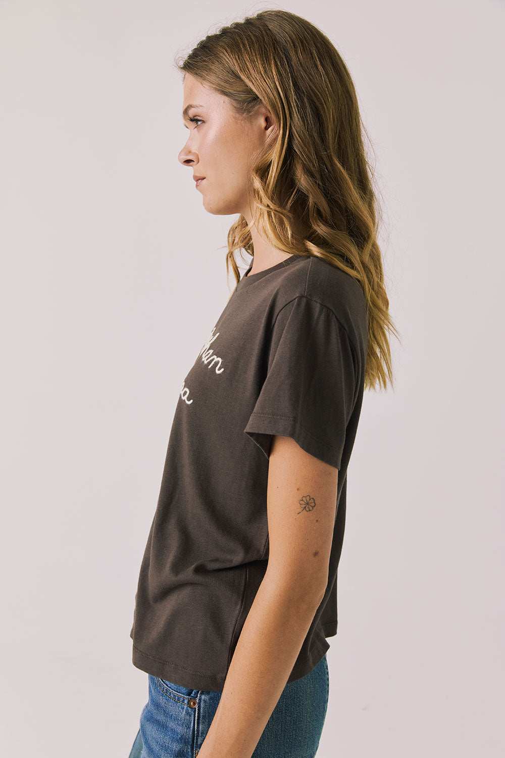 Front view of woman wearing Chaser’s brown Hot Cocoa Tee on a plain background
