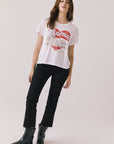 Full body view of woman wearing Chaser's white Italian slogan tee featuring red heart and Colosseum design, paired with black pants and black boots on a light background