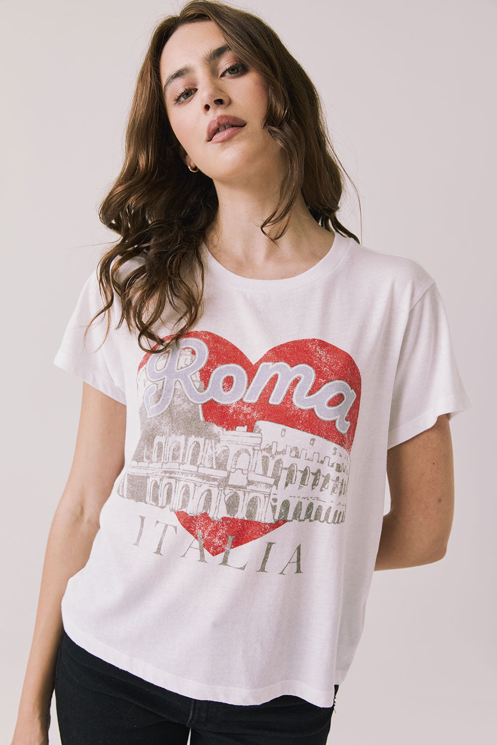 Front view of woman wearing Chaser's white Italian graphic tee with red heart, the Colosseum, and “Roma Italia” text on a light background