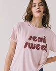 Front view of woman wearing Chaser’s Semi Sweet Pink Tee with “semi sweet” text on a light background