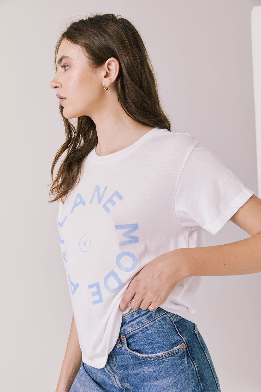Side view of woman wearing the Airplane Mode Tee with blue text on a plain background