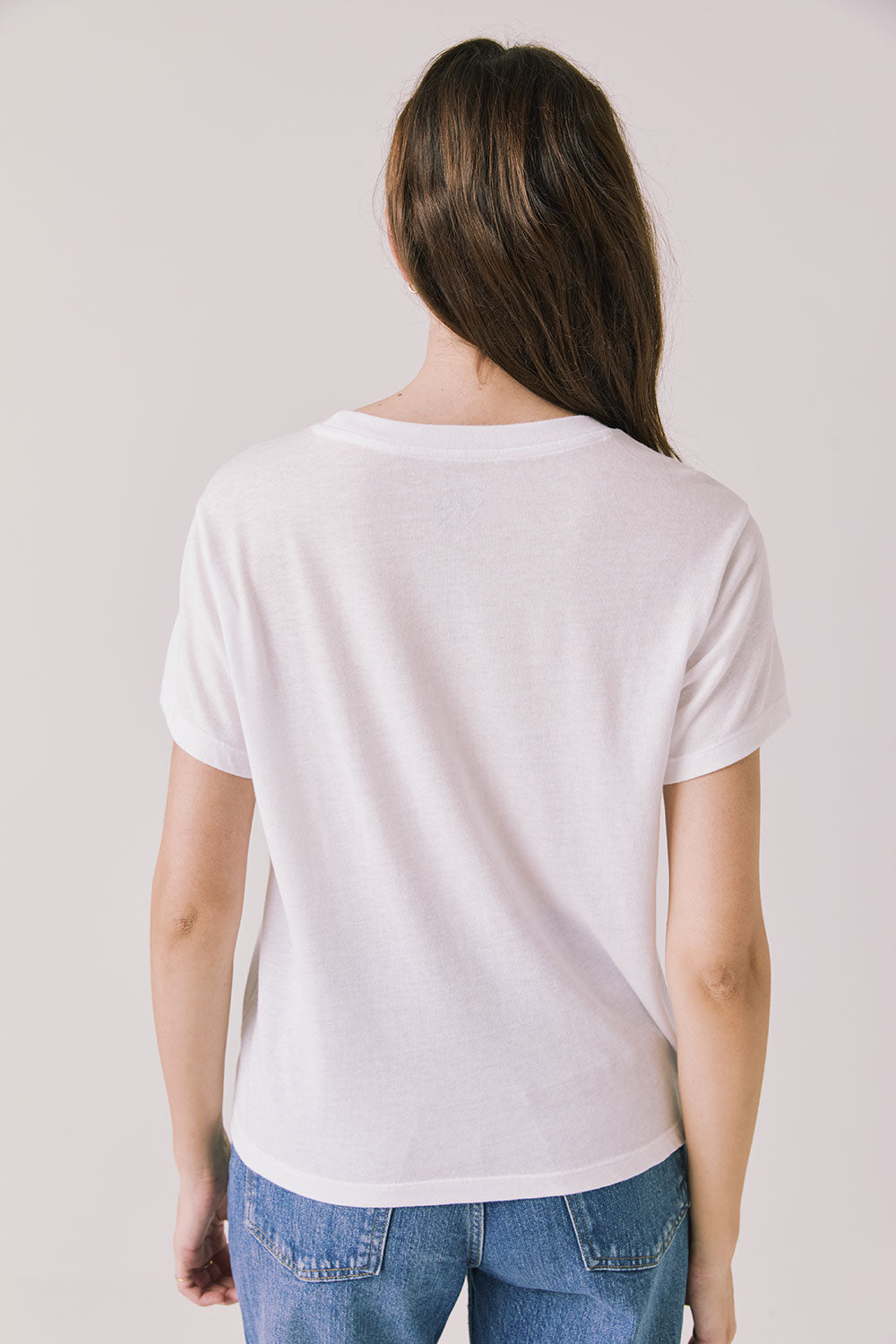 Back view of woman wearing the Airplane Mode Tee on a plain background
