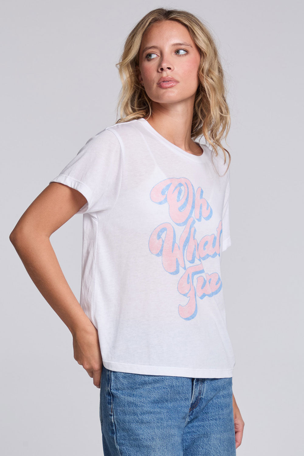 Model wearing Chaser's Oh What Fun Tee in White with pastel Oh What Fun holiday lettering, angled view
