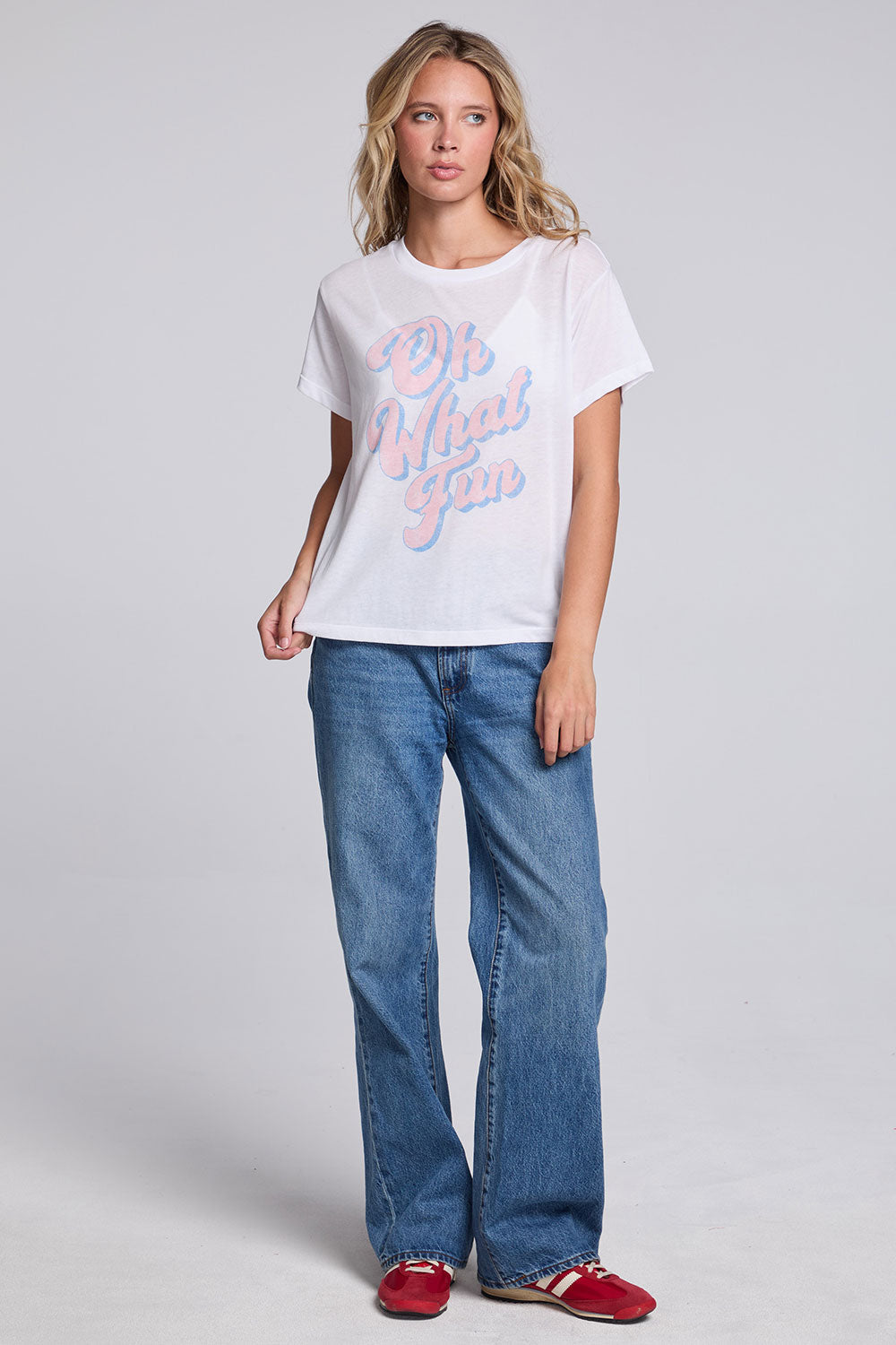 Model wearing Chaser's Oh What Fun Tee in White with pastel Oh What Fun holiday lettering, full-body view
