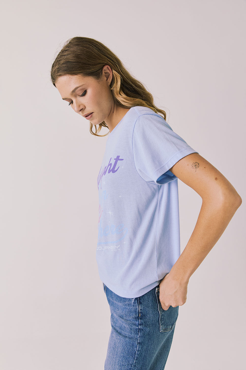 Side view of woman wearing Chaser’s Journey Midnight Train Light Blue Tee with “Midnight Going” text on a plain background
