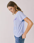 Side view of woman wearing Chaser’s Journey Midnight Train Light Blue Tee with “Midnight Going” text on a plain background
