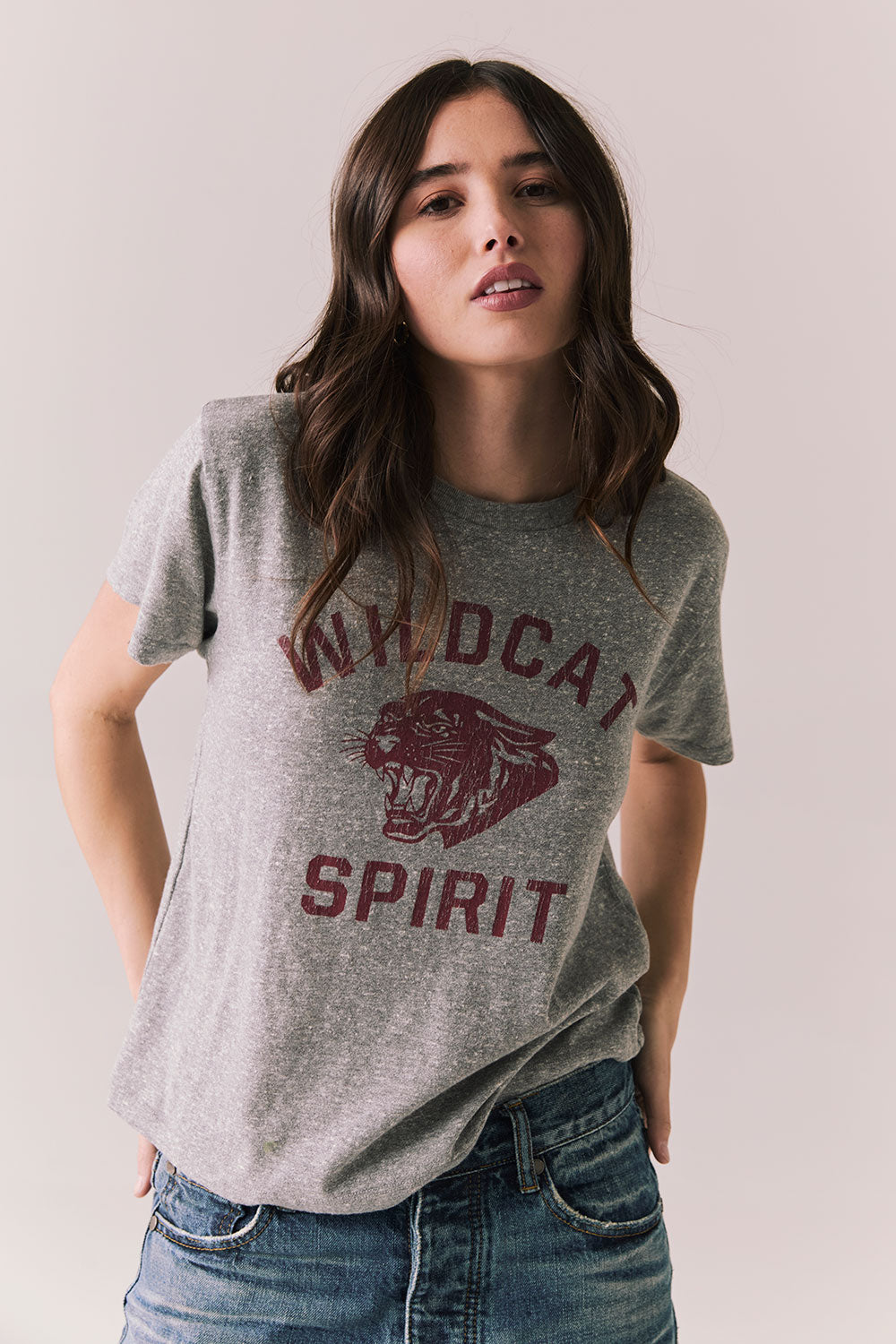Front view of model wearing Wildcat Spirit Tee in Heather Grey with maroon wildcat chest graphic against a plain background