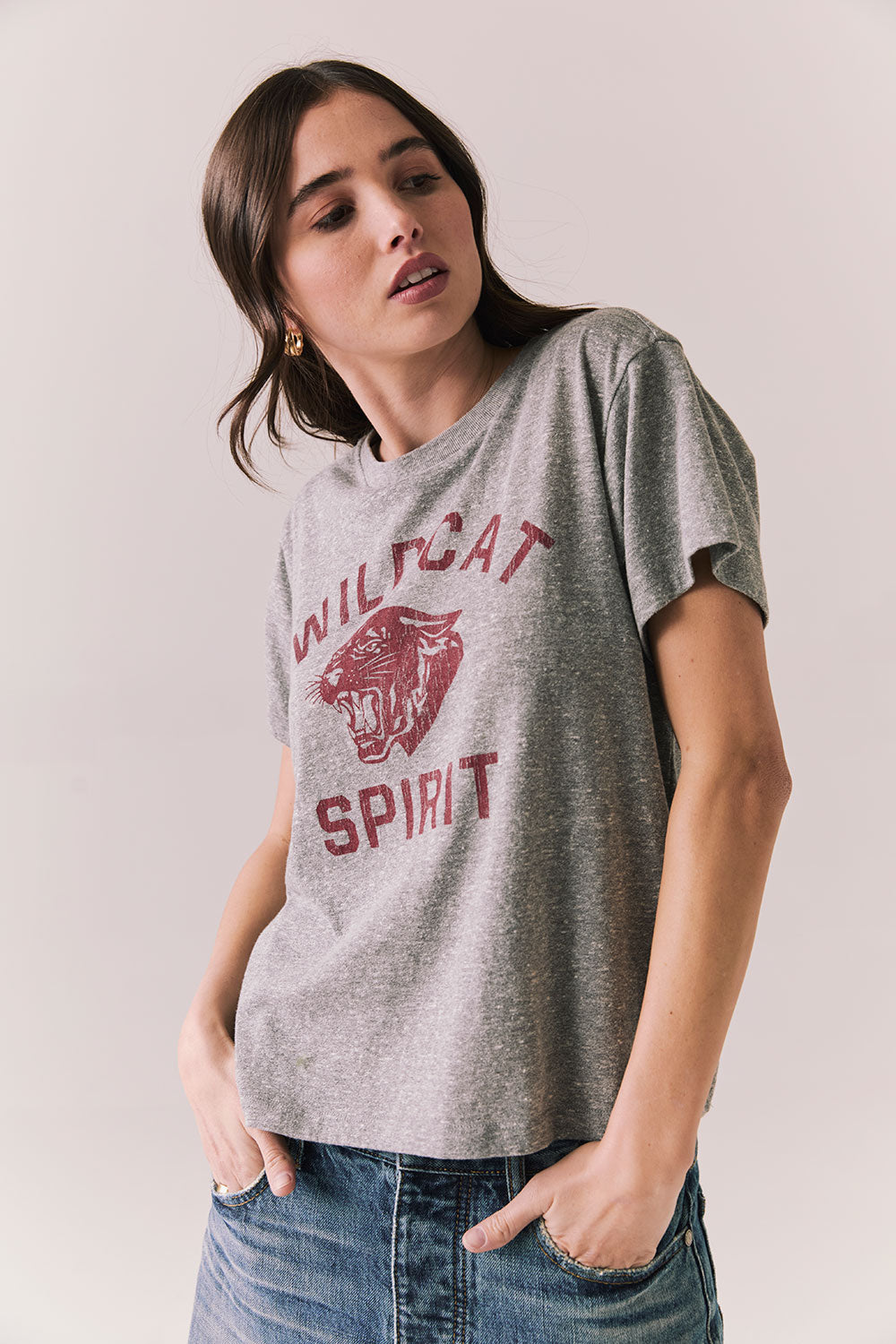 Side view of model wearing Wildcat Spirit Tee in Heather Grey with maroon wildcat chest graphic against a plain background