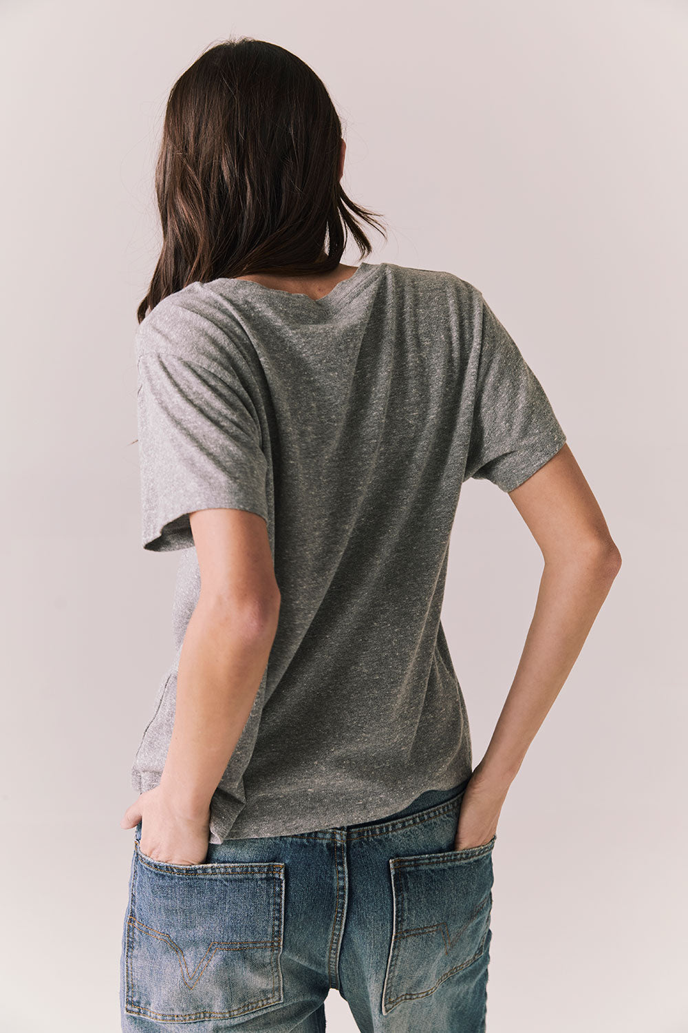 Back view of model wearing Wildcat Spirit Tee in Heather Grey with maroon wildcat chest graphic against a plain background