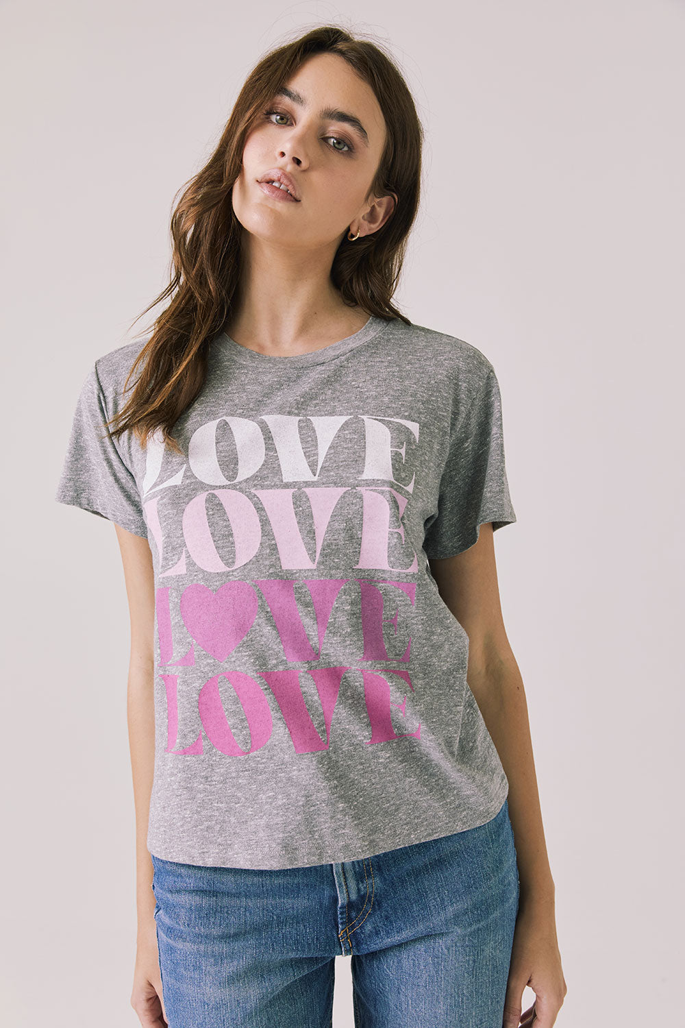 Front view of woman wearing Chaser’s Streaky Grey Love Tee with pink text on a white background