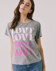 Front view of woman wearing Chaser’s Streaky Grey Love Tee with pink text on a white background