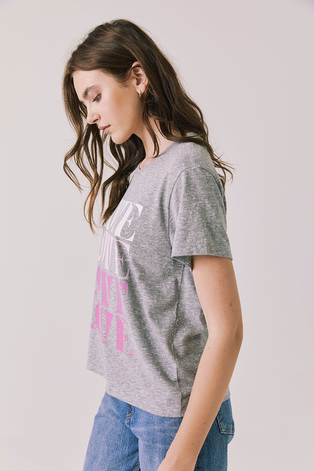 Side view of woman wearing Chaser’s Streaky Grey Love Tee with pink text on a white background